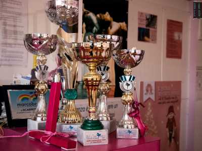 Mentre parla notiamo diversi trofei, di cui uno abbellito da una scarpetta rigorosamente rosa...